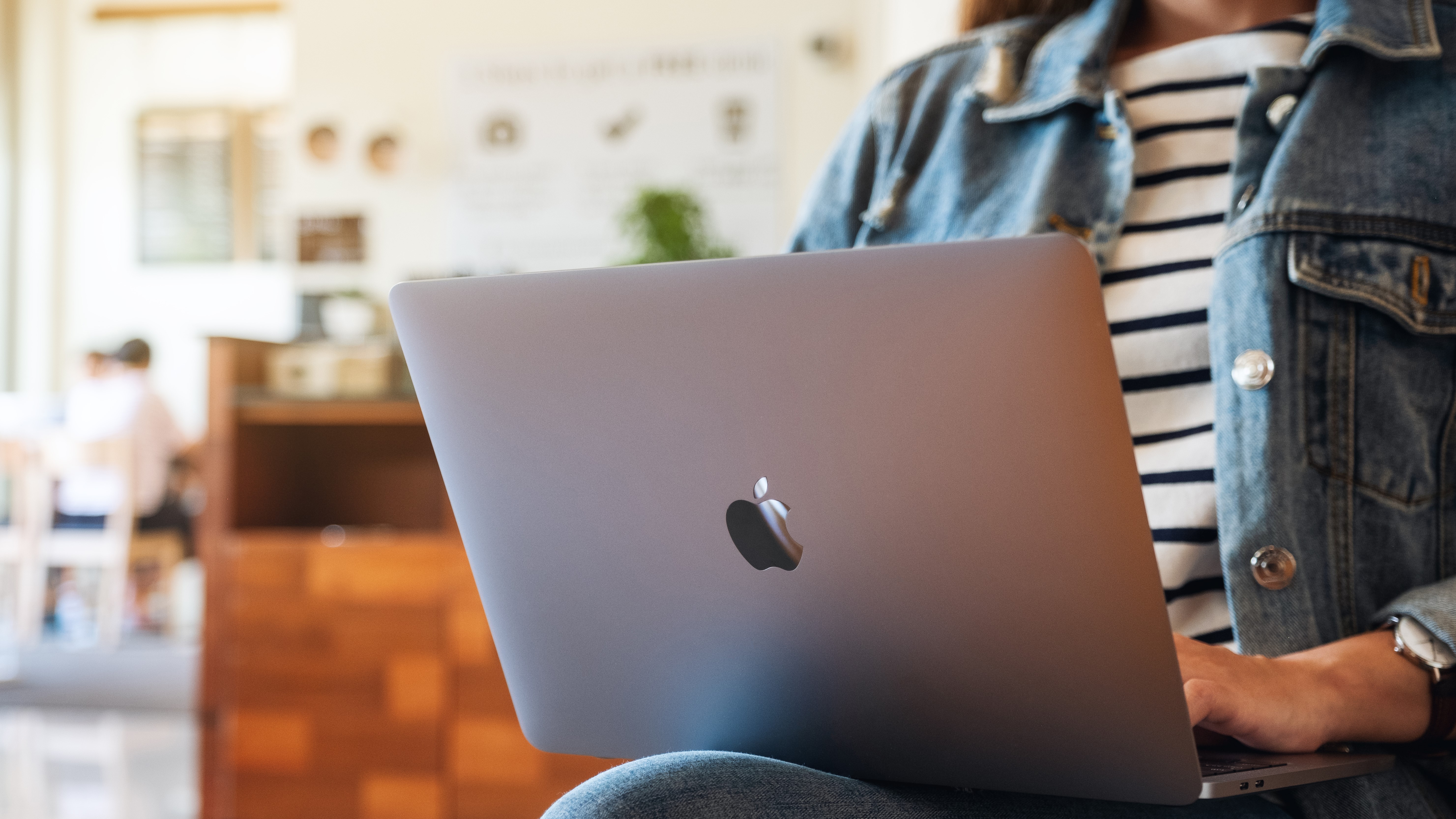 Une femme assise avec un ordinateur portable MacBook sur ses genoux