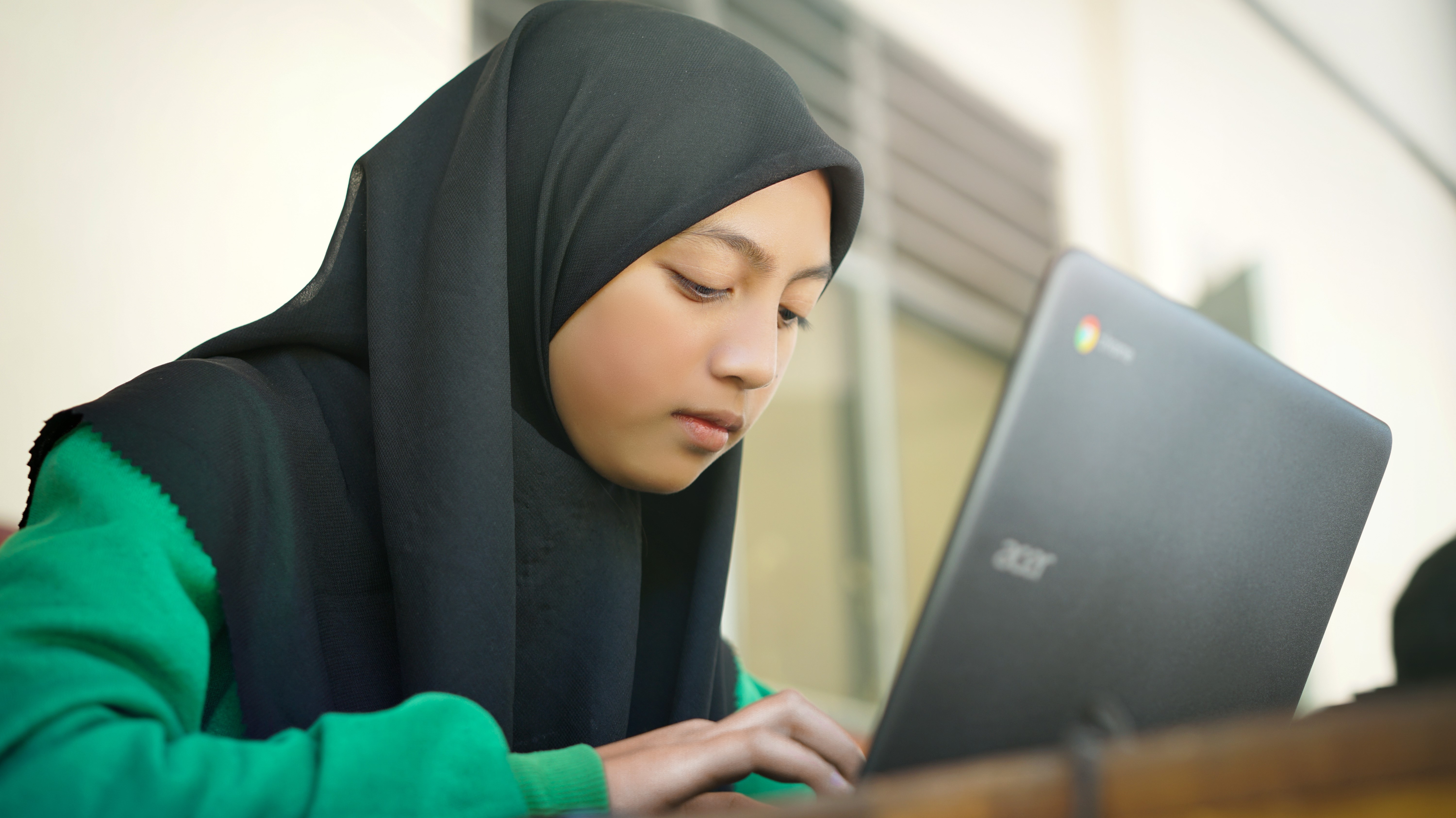 Un étudiant plus jeune étudiant éventuellement à distance à l'aide d'un ordinateur portable Chromebook